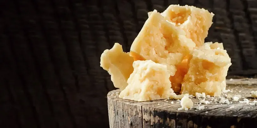 Detailní pohled na kousky zralého Parmigiano Reggiano s viditelnou zrnitostí a krystalky